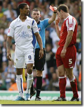 Jermaine Beckford looks on as referee Michael Oliver shows a red card to David McCracken of MK Dons