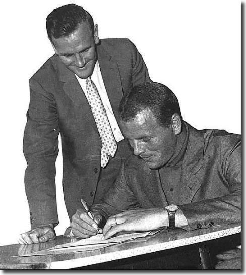 Watched by his new manager Don Revie, Charles signs to confirm his return to Elland Road