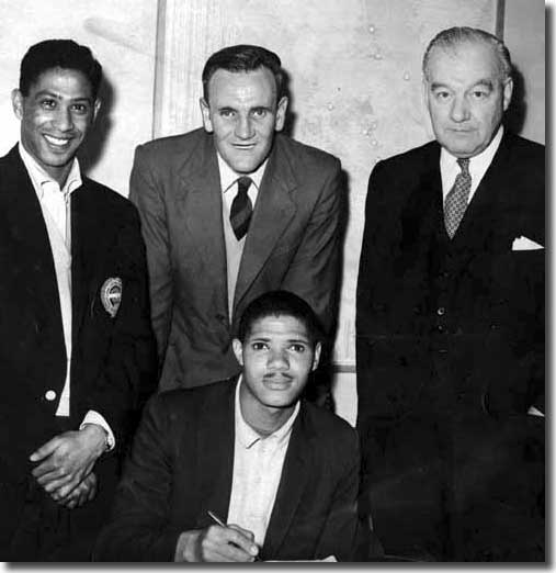 Albert Johanneson signs for United watched by Gerry Francis, Don Revie and Cyril Williamson