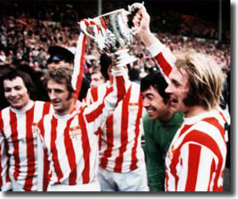 Jimmy Greenhoff and George Eastham hoist the League Cup - also pictured are full-back John Marsh and Gordon Banks