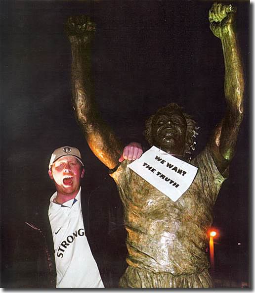 A United fan makes his point atop the statue of Billy Bremner outside Elland Road